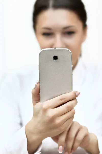 Young beautiful woman writes an SMS to your mobile phone. Close up — Stock Photo, Image