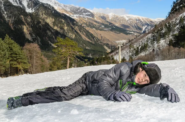 Rapaz deitado na neve — Fotografia de Stock