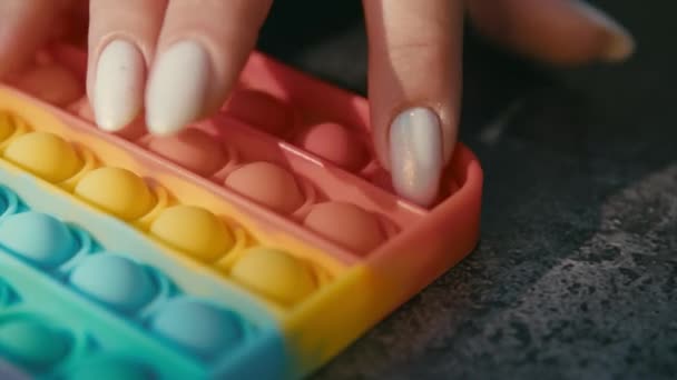 Mädchenhände spielen mit Popit-Push-Fidget-Spielzeug aus der Popblase. Beliebte pädagogische Kinderspiel Pop It mit Knöpfen und bunten Anti-Stress-Spielzeug. — Stockvideo