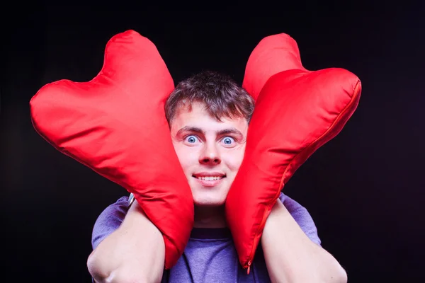 Man holding two red heart shaped pillows — Stock Photo, Image