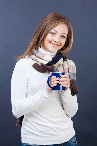 Smiling woman in scarf with cup of tea