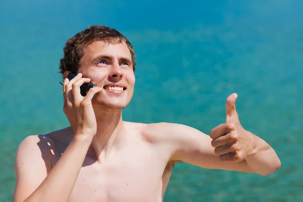Young man speaking on the phone and smiling Stock Picture