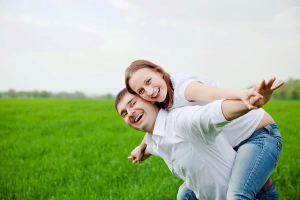 Jeune couple faisant un avion dans le champ vert — Photo