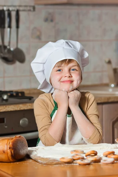 シェフの帽子で可愛い女の子が甘いケーキを作る — ストック写真