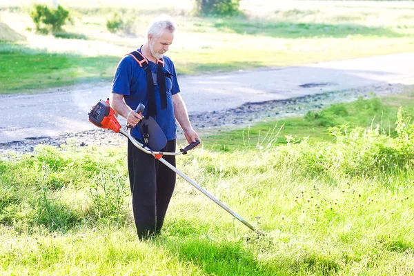 Homem sênior com cortador de grama — Fotografia de Stock