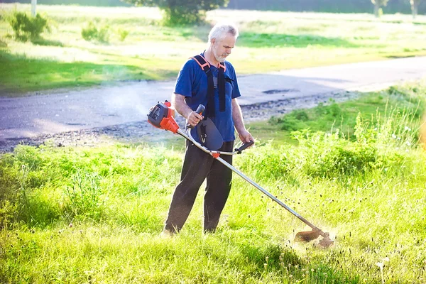 Homem sênior com cortador de grama — Fotografia de Stock