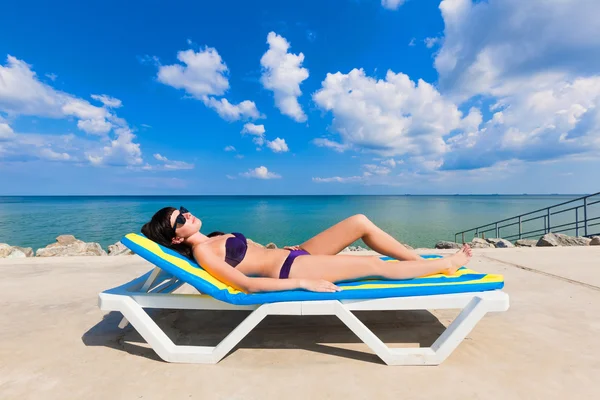 Mooi meisje in een bikini liggend op een strandstoel — Stockfoto