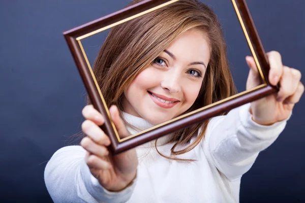 Beautiful girl with a photo frame on a dark blue background — Stock Photo, Image