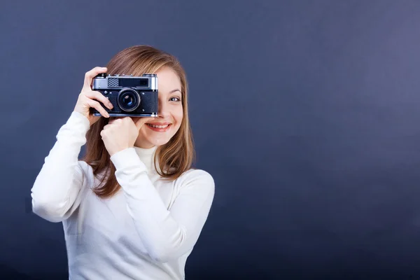 Hermosa chica con una cámara de fotos sobre un fondo azul oscuro — Foto de Stock