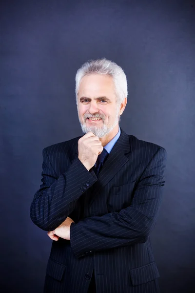 Studio shot of a smiling business man with crossed arms on the d — Stock Photo, Image