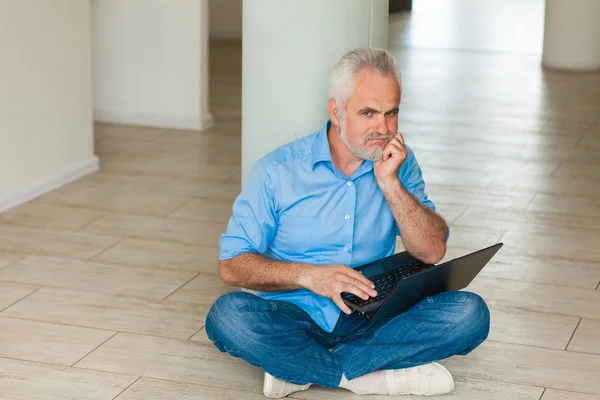 Old man with notebook sitting on the floor — Stock Photo, Image