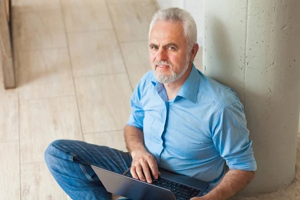 Stary człowiek z notebooka, siedząc na podłodze — Zdjęcie stockowe