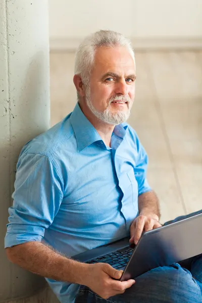 Old man with notebook sitting on the floor — Stock Photo, Image