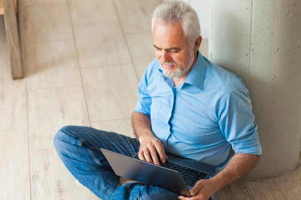 Old man with notebook sitting on the floor — Stock fotografie