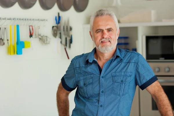 Alter Mann lächelt in die Küche — Stockfoto