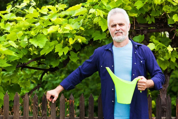 Portrait of senior man with watering can in garden