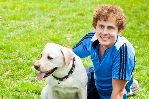 Завиток усміхнений чоловік зі своїм собакою сидить надворі — стокове фото