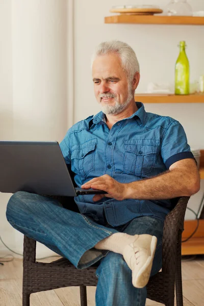 Senior man with notebook sitting at the kitchen — Stock Photo, Image