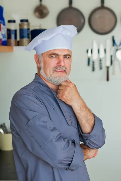 Chef amichevole sorridente sulla sua cucina — Foto Stock