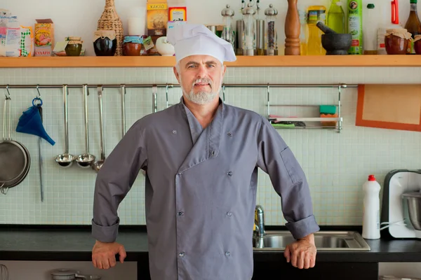 Vriendelijke chef-kok glimlachend op zijn keuken — Stockfoto