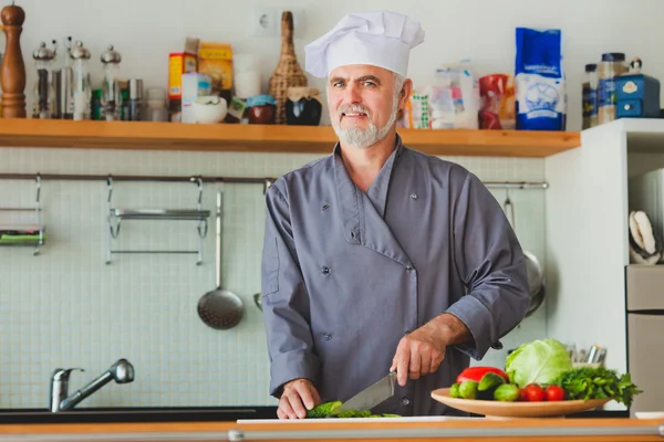 Vriendelijke chef-kok voorbereiding van groenten in zijn keuken — Stockfoto