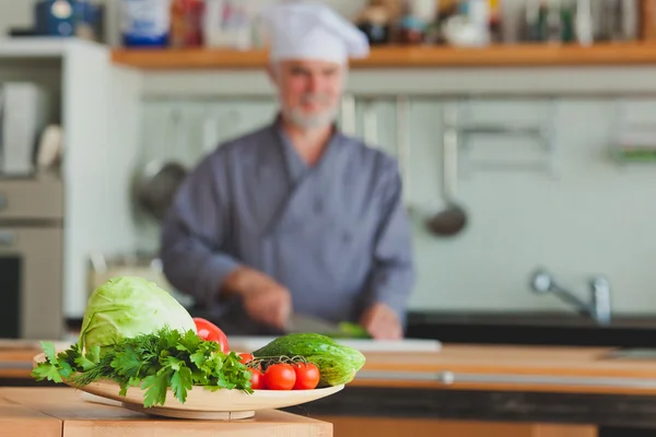 Chef amigável preparando legumes em sua cozinha — Fotografia de Stock