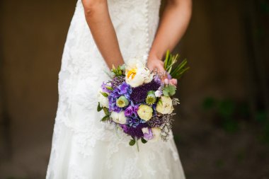 Bir buket çiçekli beyaz elbiseli güzel gelin.