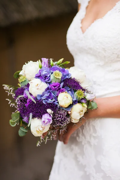 Bela noiva em um vestido branco com um buquê de flores — Fotografia de Stock