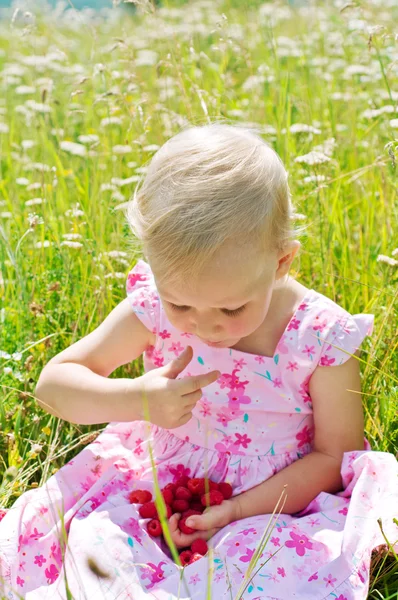 Маленькая девочка ест малину — стоковое фото
