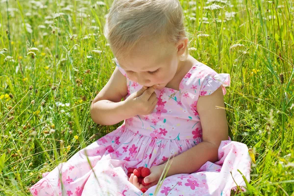 Little girl eating raspberries — Stock Photo, Image