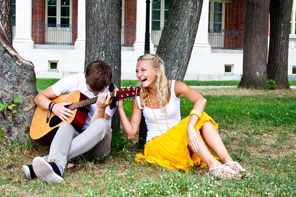Man and woman with a guitar in the park — Stock Photo, Image