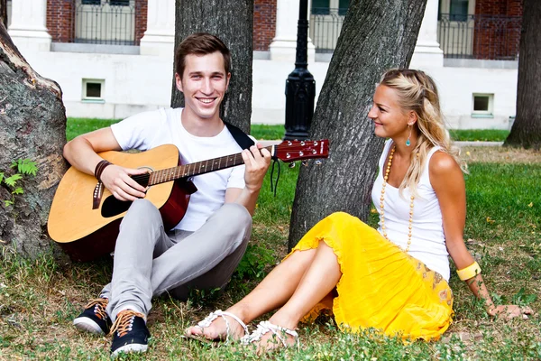 Man and woman with a guitar in the park — Stock Photo, Image