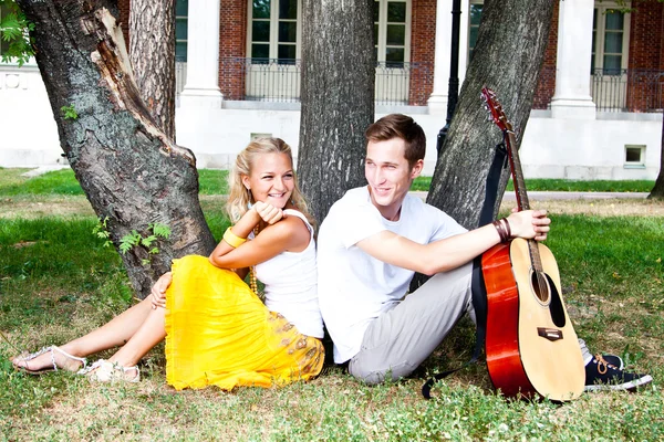 Man and woman with a guitar in the park — Stock Photo, Image