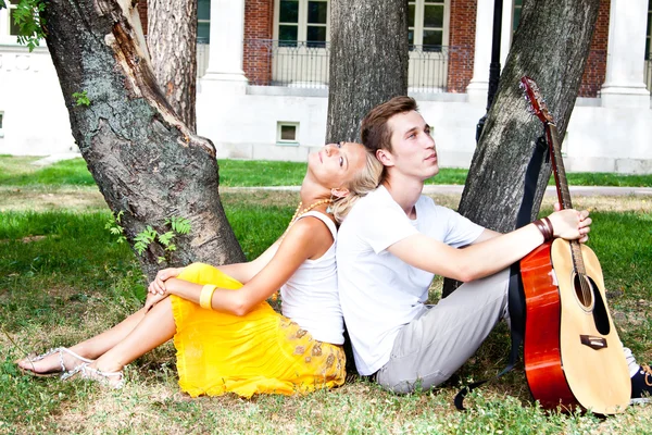 Man and woman with a guitar in the park — Stock Photo, Image