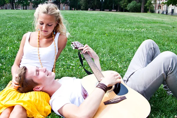 Uomo e donna con una chitarra nel parco — Foto Stock