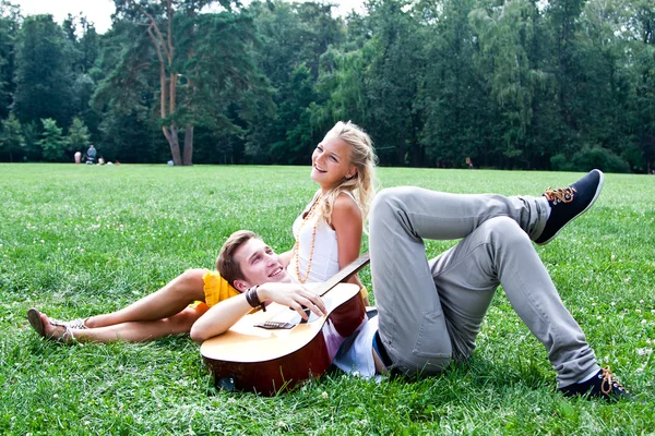 Man and woman with a guitar in the park — Stock Photo, Image