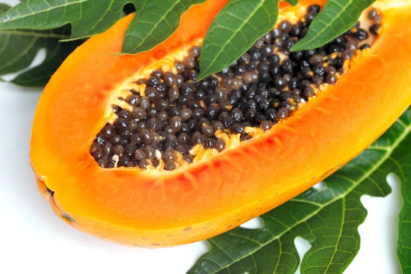 Papaya madura con semillas y hojas verdes aisladas sobre un fondo blanco —  Fotos de Stock