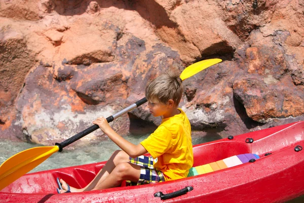 快乐的小男孩在河上划独木舟和享受可爱的汇总 免版税图库照片