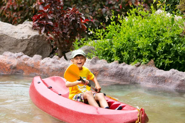 Счастливый мальчик, катающийся на байдарке по реке и наслаждающийся прекрасным летом Стоковое Фото