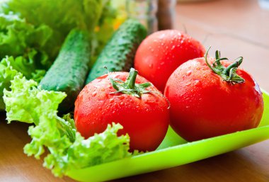 een paar rijpe tomaten en komkommers op tafel