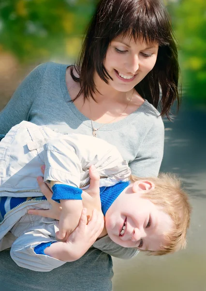 Jovem mãe brincando com seu filho bebê no parque — Fotografia de Stock