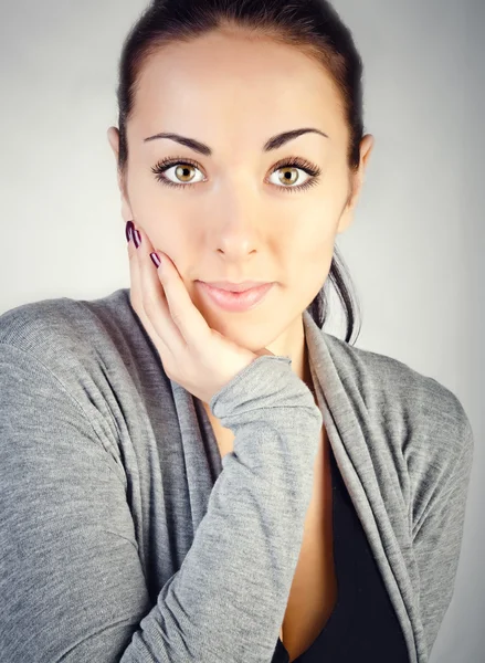 Portret van een mooie brunette meisje op een grijze achtergrond — Stockfoto