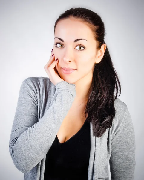 Retrato de una hermosa joven morena sonriente en una ba gris — Foto de Stock