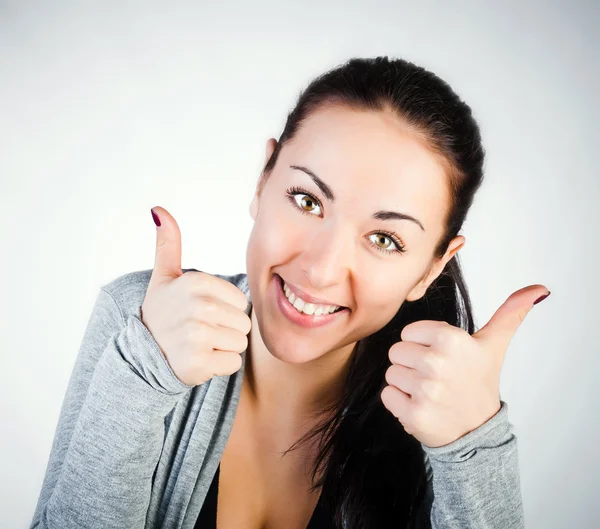 Ritratto di una giovane ragazza sorridente bruna con i pollici in su — Foto Stock