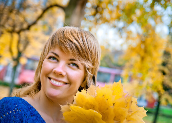 young smiling girl in fall maple leaves