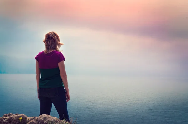 Young girl standing on a cliff above the sea — Stock Photo, Image