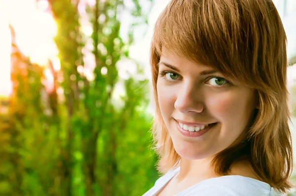 Face of a beautiful young girl on the background of trees — Stock Photo, Image