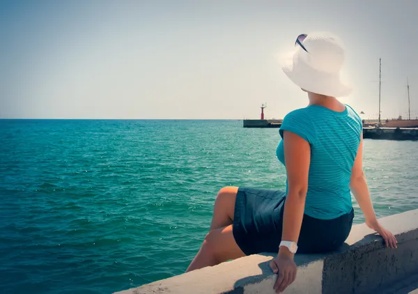 Uma jovem sentada na doca observando o mar — Fotografia de Stock