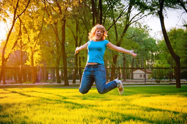 Cheerful young girl jumping in the park — Stock Photo, Image