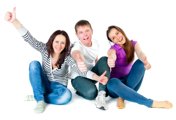 Young friends sitting on the floor and showing thumbs up Royalty Free Stock Photos